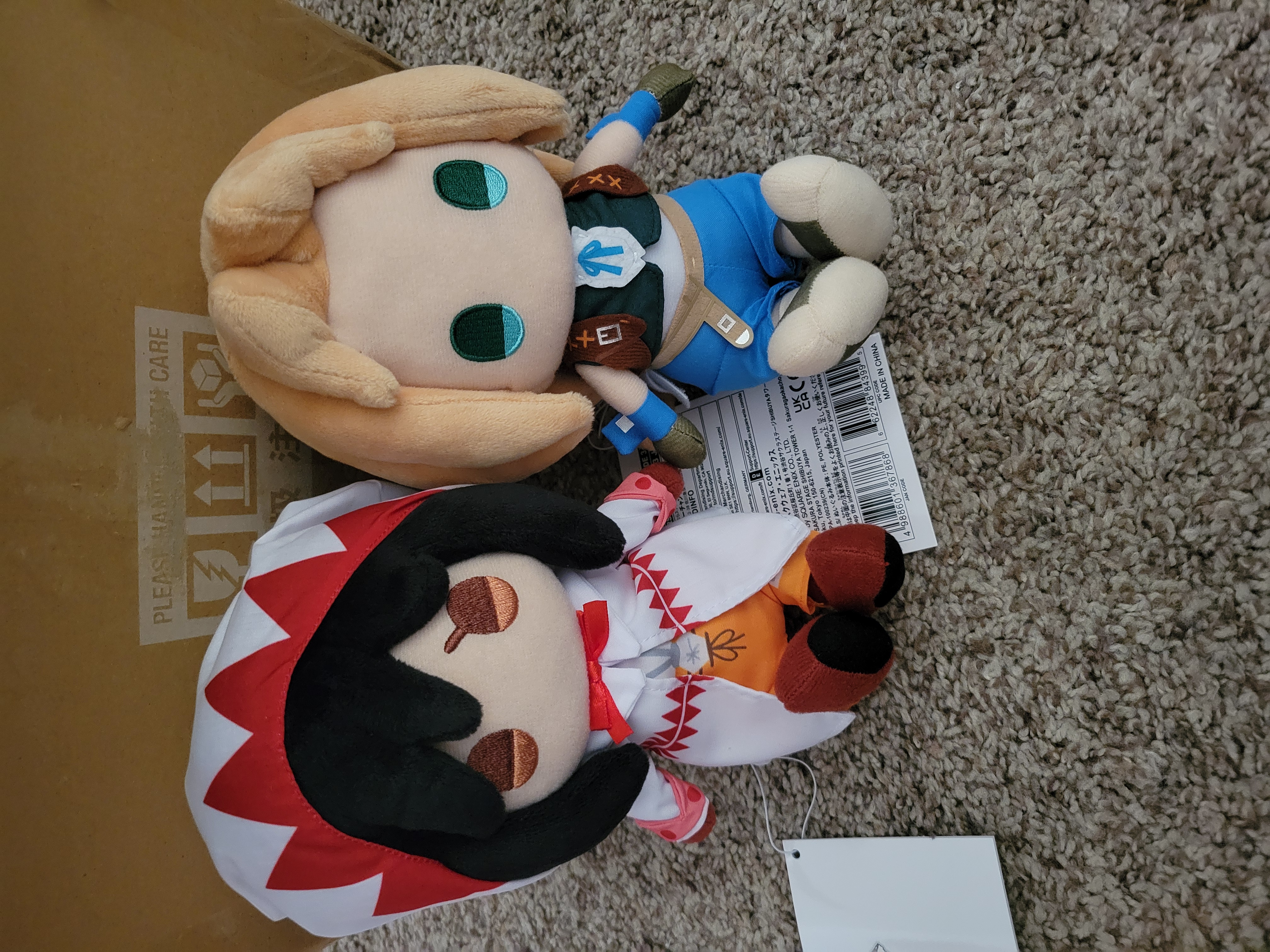 Garnet and Zidane plush sitting aside cardboard box.